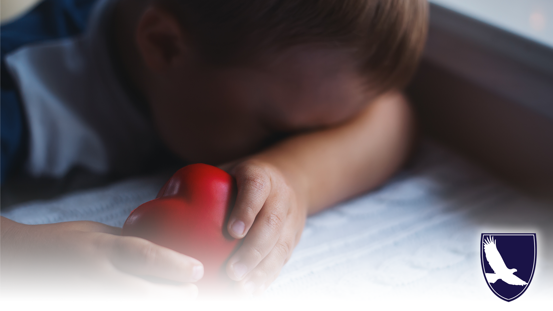 Child facedown on arm holding heart shaped stress ball